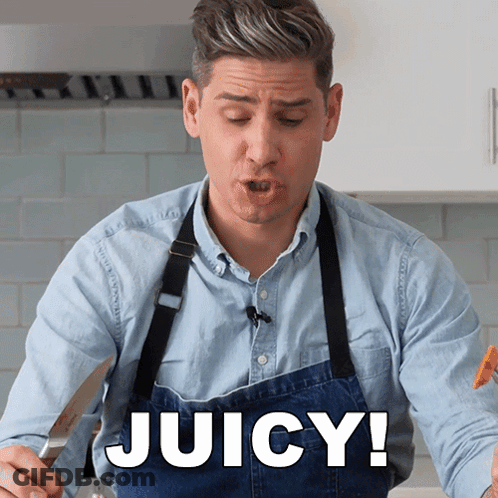 A Man Wearing A Blue Apron Says Juicy In A Kitchen GIF