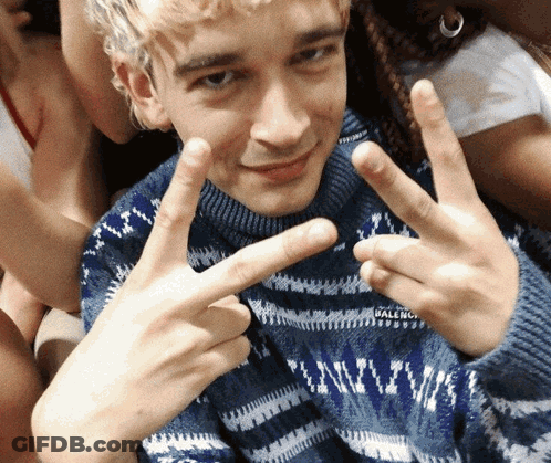 A Man Wearing A Blue Balenciaga Sweater Is Giving The Peace Sign GIF