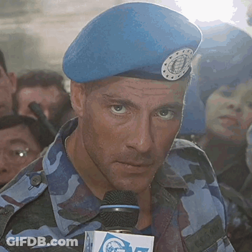 A Man Wearing A Blue Beret Is Holding A Microphone With A Box That Says Cnn On It GIF