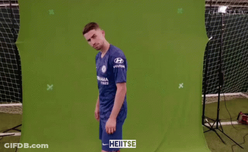A Man Wearing A Blue Chelsea Jersey Stands In Front Of A Green Screen GIF
