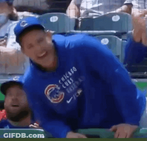 A Man Wearing A Blue Chicago Cubs Sweatshirt Is Sitting In The Dugout . GIF