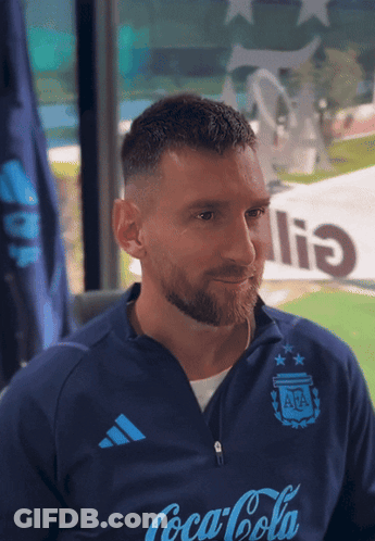 A Man Wearing A Blue Coca Cola Shirt Looks At The Camera GIF