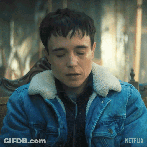 A Man Wearing A Blue Denim Jacket With A Sherpa Collar Is Sitting On A Chair With His Eyes Closed . GIF