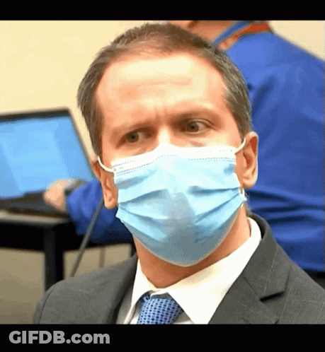 A Man Wearing A Blue Face Mask Looks At The Camera GIF