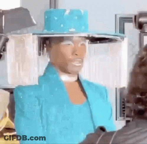 A Man Wearing A Blue Hat And A Blue Jacket Is Standing In Front Of A Camera . GIF