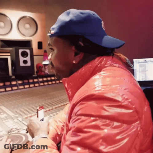 A Man Wearing A Blue Hat And A Red Jacket Sits In Front Of A Mixer GIF