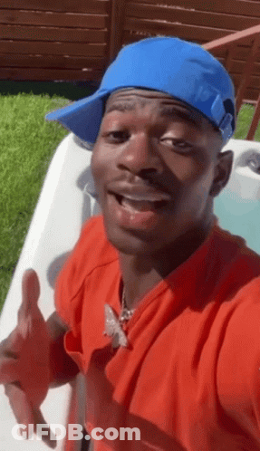 A Man Wearing A Blue Hat And A Red Shirt Is Standing Next To A Hot Tub GIF