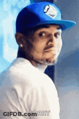 A Man Wearing A Blue Hat And A White Shirt Is Making A Sorry Gesture GIF