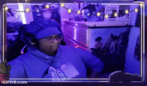 A Man Wearing A Blue Hat And Glasses Is Sitting In Front Of A Computer Screen . GIF