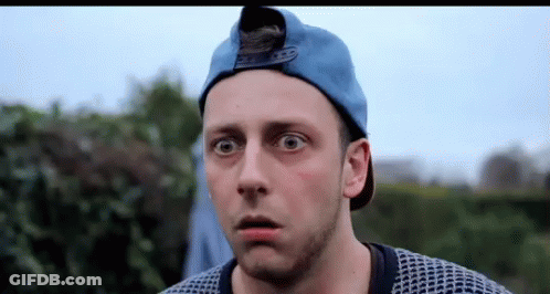A Man Wearing A Blue Hat And Sweater Is Making A Surprised Face . GIF