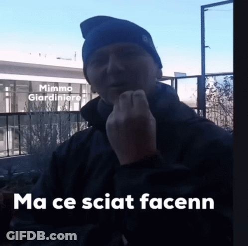 A Man Wearing A Blue Hat Is Giving The Middle Finger In Front Of A Building That Says Mimmo Giardiniere On It GIF