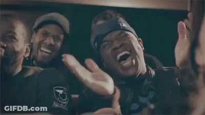 A Man Wearing A Blue Headband With The Letter G On It Is Laughing With Two Other Men . GIF