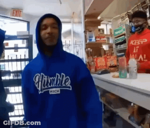 A Man Wearing A Blue Humble Mech Hoodie Stands In Front Of A Counter GIF