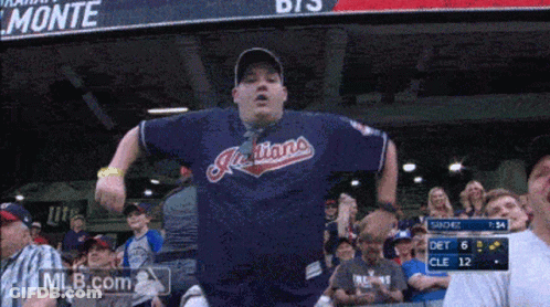 A Man Wearing A Blue Indians Jersey Stands In The Stands GIF
