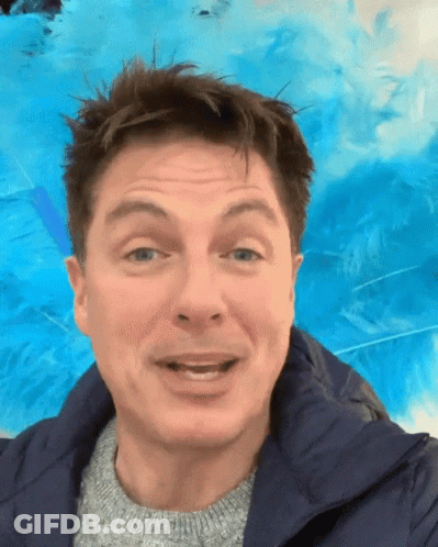 A Man Wearing A Blue Jacket And A Grey Sweater Is Smiling GIF