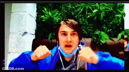 A Man Wearing A Blue Jacket And A Mask Is Making A Funny Face While Talking On A Video Call . GIF
