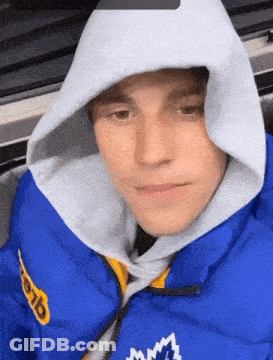 A Man Wearing A Blue Jacket And A White Hoodie With The Word Mlb On It GIF