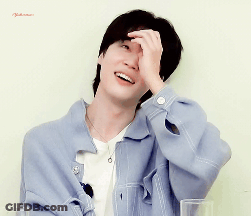 A Man Wearing A Blue Jacket And A White Shirt Is Smiling And Covering His Face With His Hand GIF