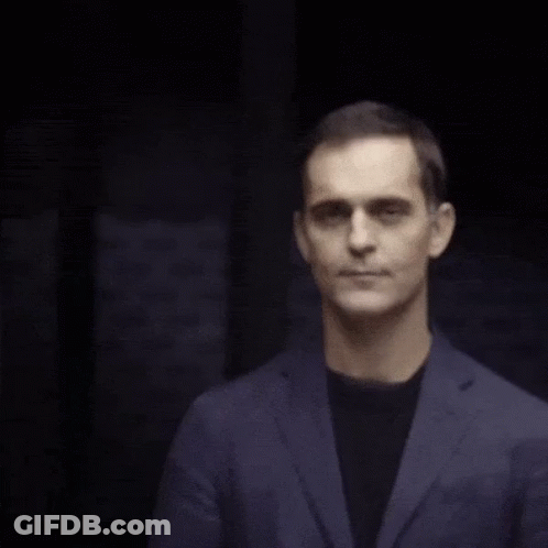 A Man Wearing A Blue Jacket And Black Shirt Is Smiling GIF