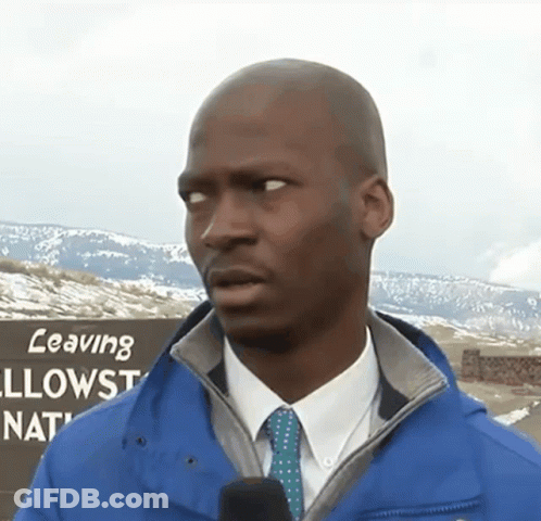 A Man Wearing A Blue Jacket And Tie Stands In Front Of A Sign That Says Leaving Yellowstone National Park GIF