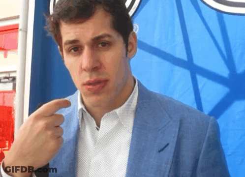 A Man Wearing A Blue Jacket And White Shirt Is Pointing At Something GIF