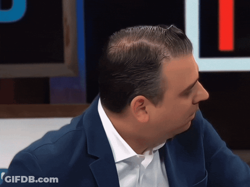 A Man Wearing A Blue Jacket And White Shirt Looks To The Side GIF