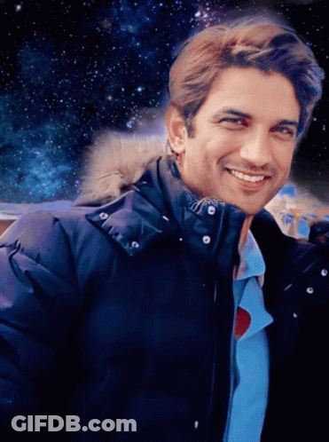 A Man Wearing A Blue Jacket With A Fur Hood Smiles GIF