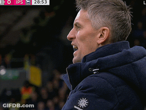 A Man Wearing A Blue Jacket With A Sun On The Sleeve Watches A Soccer Game GIF