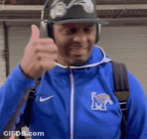 A Man Wearing A Blue Jacket With The Letter M On It Gives A Thumbs Up GIF