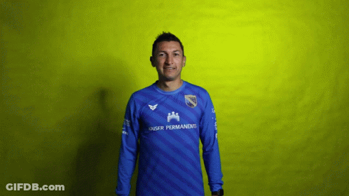 A Man Wearing A Blue Kaiser Permanent Jersey Stands In Front Of A Yellow Background GIF