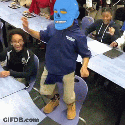 A Man Wearing A Blue Mask Is Dancing In Front Of A Group Of Children GIF