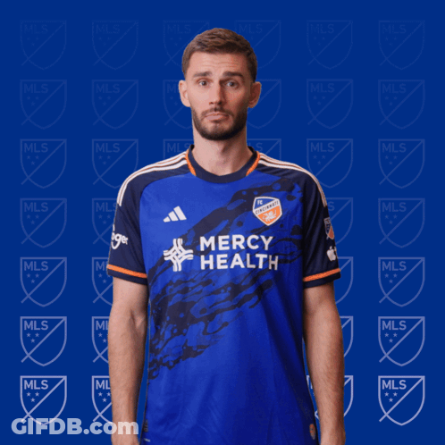 A Man Wearing A Blue Mercy Health Jersey Makes A Funny Face GIF