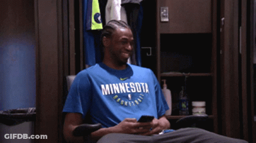 A Man Wearing A Blue Minnesota Basketball Shirt Looks At His Phone GIF