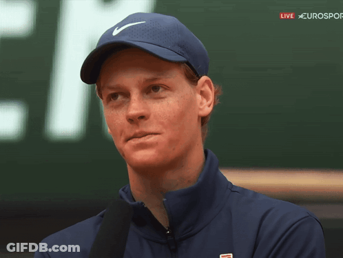 A Man Wearing A Blue Nike Hat Stands In Front Of A Sign That Says Eurosport GIF