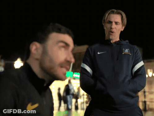 A Man Wearing A Blue Nike Jacket Talks To Another Man GIF