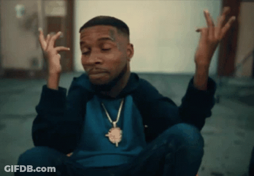 A Man Wearing A Blue Shirt And A Gold Necklace Is Making A Face GIF