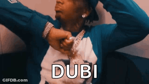 A Man Wearing A Blue Shirt And A Watch Is Holding A Chain Around His Neck And The Word Dubi Is Above Him . GIF