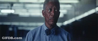 A Man Wearing A Blue Shirt And Bow Tie Is Looking At The Camera . GIF