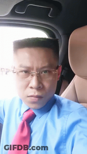 A Man Wearing A Blue Shirt And Red Tie Is Sitting In The Driver 'S Seat Of A Car GIF