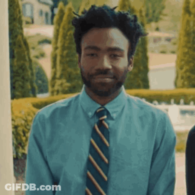 A Man Wearing A Blue Shirt And Striped Tie Smiles GIF