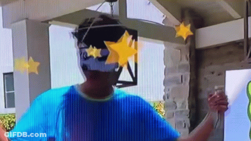 A Man Wearing A Blue Shirt And Sunglasses Is Standing In Front Of A Building With Stars On His Face . GIF
