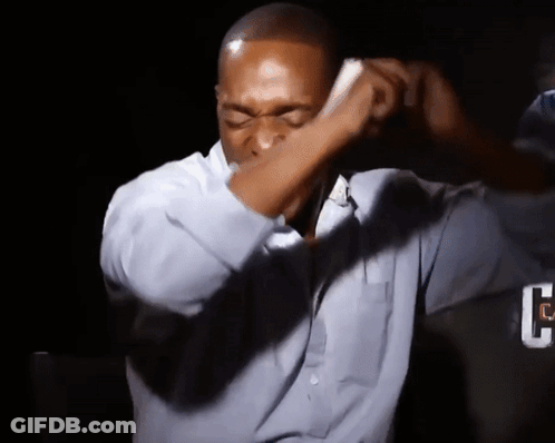 A Man Wearing A Blue Shirt Is Covering His Face With His Hand GIF