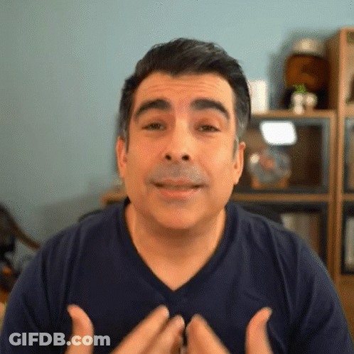 A Man Wearing A Blue Shirt Is Making A Face With His Hands GIF