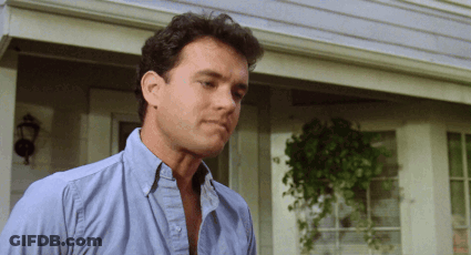 A Man Wearing A Blue Shirt Is Standing In Front Of A House GIF