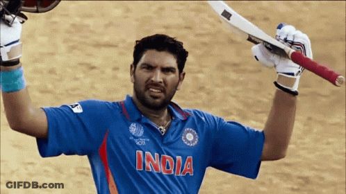 A Man Wearing A Blue Shirt That Says India Holds Up His Bat GIF