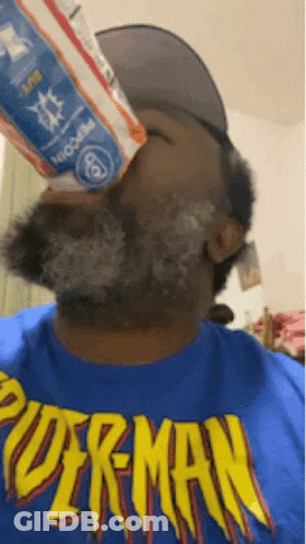 A Man Wearing A Blue Shirt That Says Superman Is Drinking From A Bottle GIF