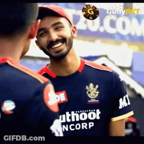 A Man Wearing A Blue Shirt That Says Uthoot Ncorp Is Smiling While Talking To Another Man . GIF