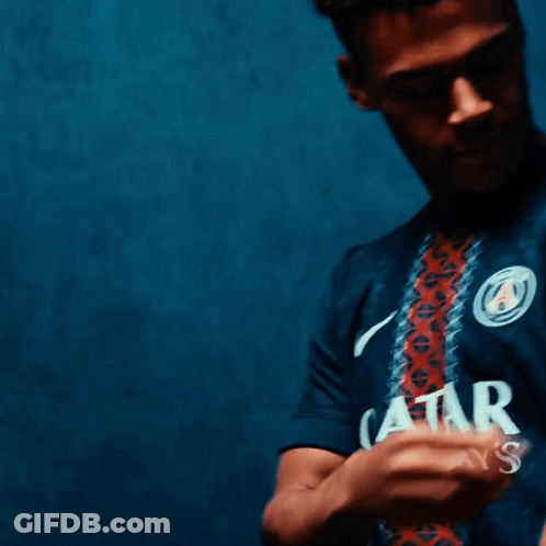 A Man Wearing A Blue Shirt With A Circle On The Front GIF
