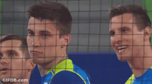 A Man Wearing A Blue Shirt With The Letter N On It Looks Behind A Net GIF