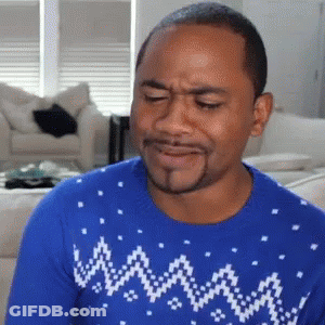 A Man Wearing A Blue Sweater Is Making A Funny Face In A Living Room . GIF